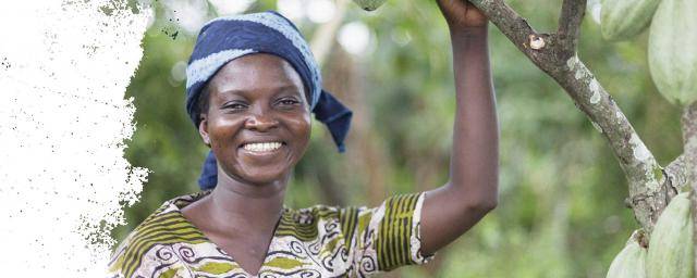 woman smiling holding onto cacao plant branch